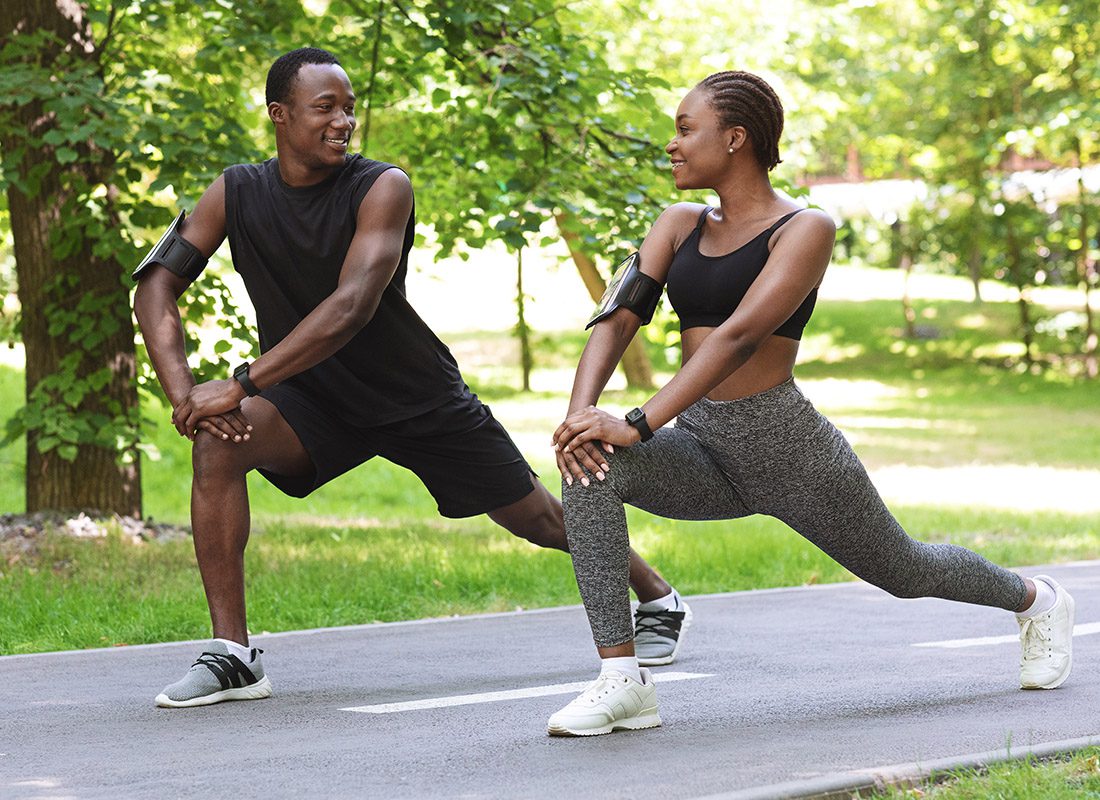 Employee Benefits - Athletic Couple Stretch Before Starting Their Jog in the Park
